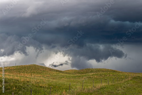 Low and ragged storm clouds in the sky over hills and prairie in Nebraska.