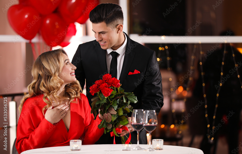 Φωτογραφία Man presenting roses to his beloved woman in restaurant at Valentine's day dinne