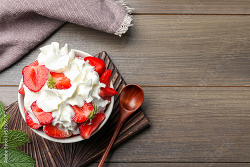 Delicious strawberries with whipped cream served on wooden table, flat lay. Space for text