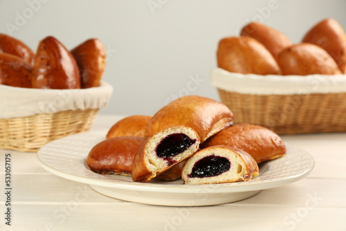 Delicious baked patties with jam on white wooden table photo