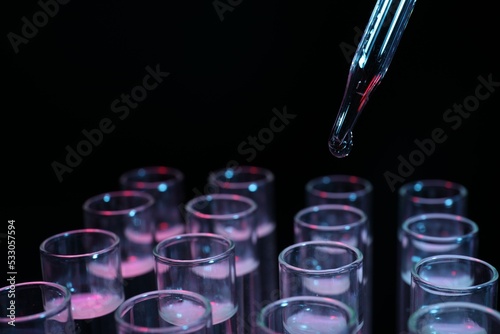Dripping reagent into test tube on black background, closeup. Laboratory analysis