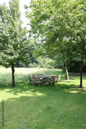 Empty wooden table with bench and chairs in garden © New Africa