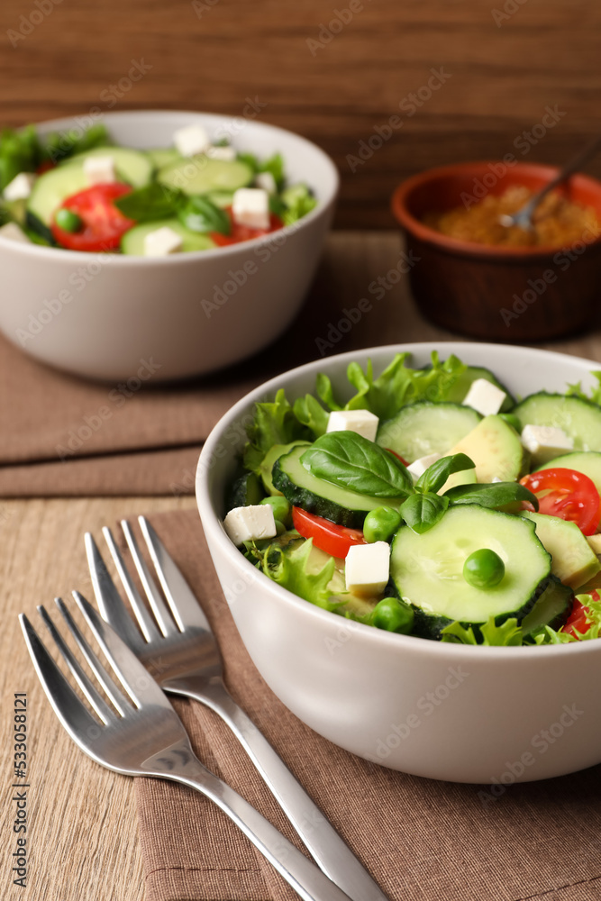 Tasty fresh salad with cucumber served on wooden table Tasty fresh salad with cucumber served on wooden table