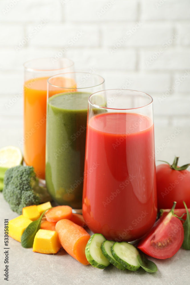 Different tasty juices and fresh ingredients on grey table against brick wall Different tasty juices and fresh ingredients on grey table against brick wall