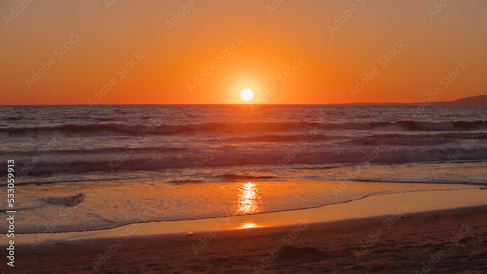 Sunset seen at Santa Monica Beach, CA, USA in Summer 2022. Beautiful orange tones in the twilight sky. Sun in perfect circle sets into the Pacific Ocean. Sunset seen at Santa Monica Beach, CA, USA in Summer 2022. Beautiful orange tones in the twilight sky. Sun in perfect circle sets into the Pacific Ocean.
