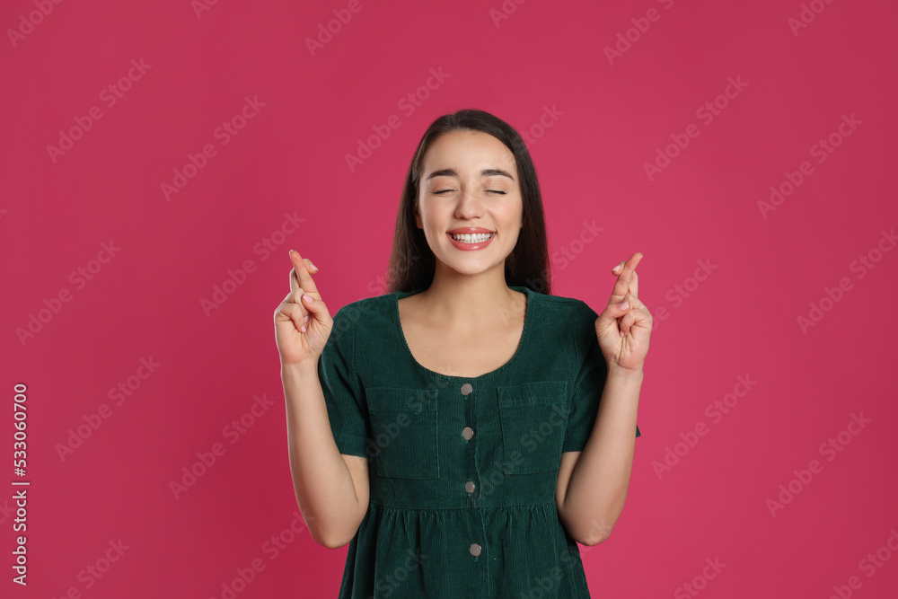 Woman with crossed fingers on pink background. Superstition concept Woman with crossed fingers on pink background. Superstition concept