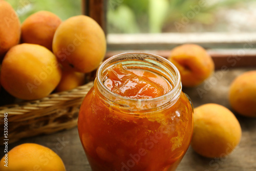 Jar of delicious jam and fresh ripe apricots on wooden table indoors, closeup. Fruit preserve
