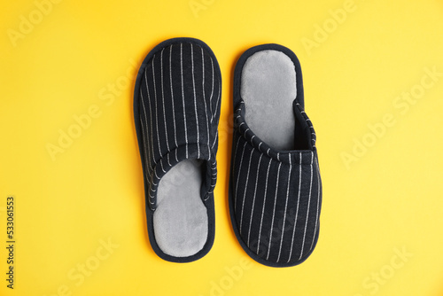 Pair of stylish slippers on yellow background, top view