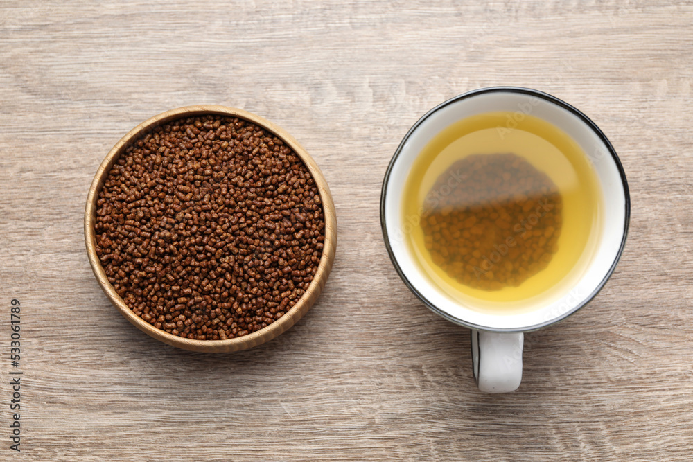 Buckwheat tea in cup and bowl with granules on wooden table, flat lay Buckwheat tea in cup and bowl with granules on wooden table, flat lay
