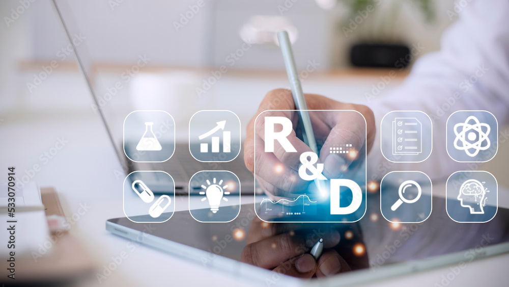 Hand of businessman holding a pen pointing to R and D icon for Research and Development on laptop screen. Manage costs more efficiently. R and D innovation concept. Hand of businessman holding a pen pointing to R and D icon for Research and Development on laptop screen. Manage costs more efficiently. R and D innovation concept.