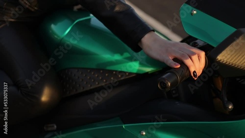 Crop anonymous woman starting motorbike in sunlight