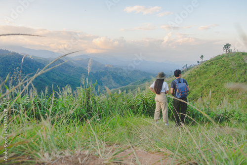 Happy young couple watching the sunset in the mountains at Mae Wong National Park, Kamphaeng Phet, Thailand