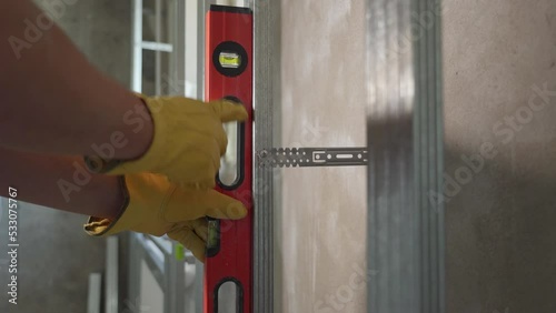 A worker checks the vertical plane with a red construction level