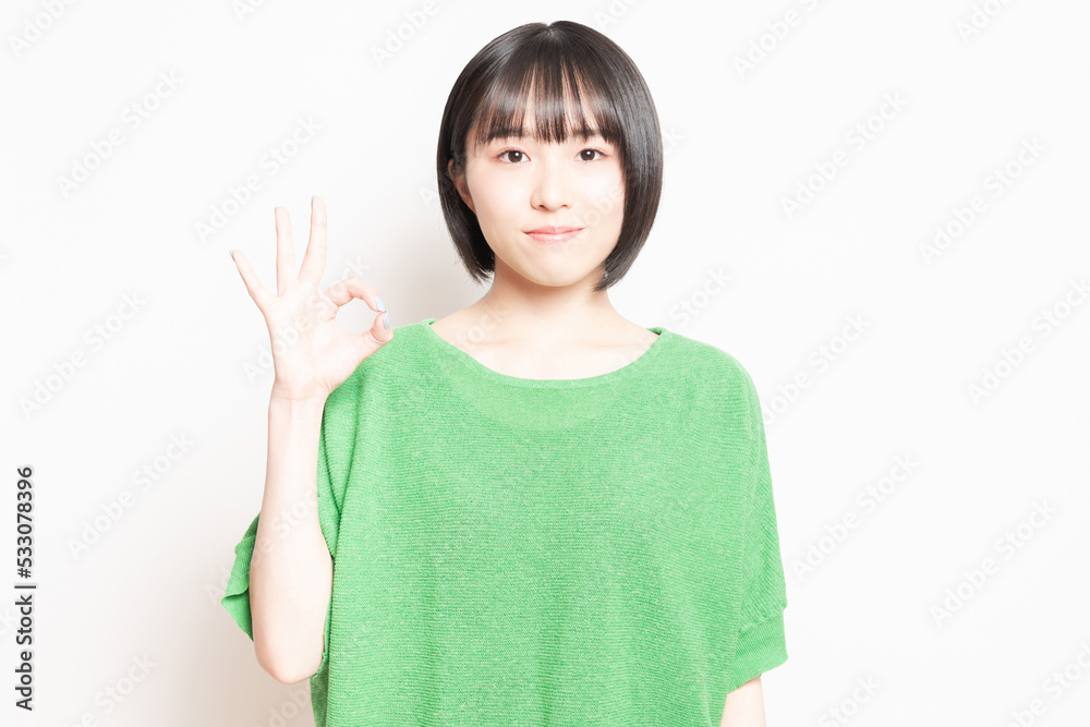 白背景の前でOKのポーズをする若い女性 白背景の前でOKのポーズをする若い女性
