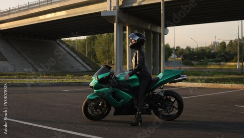 Anonymous cool woman sitting on motorbike on city street