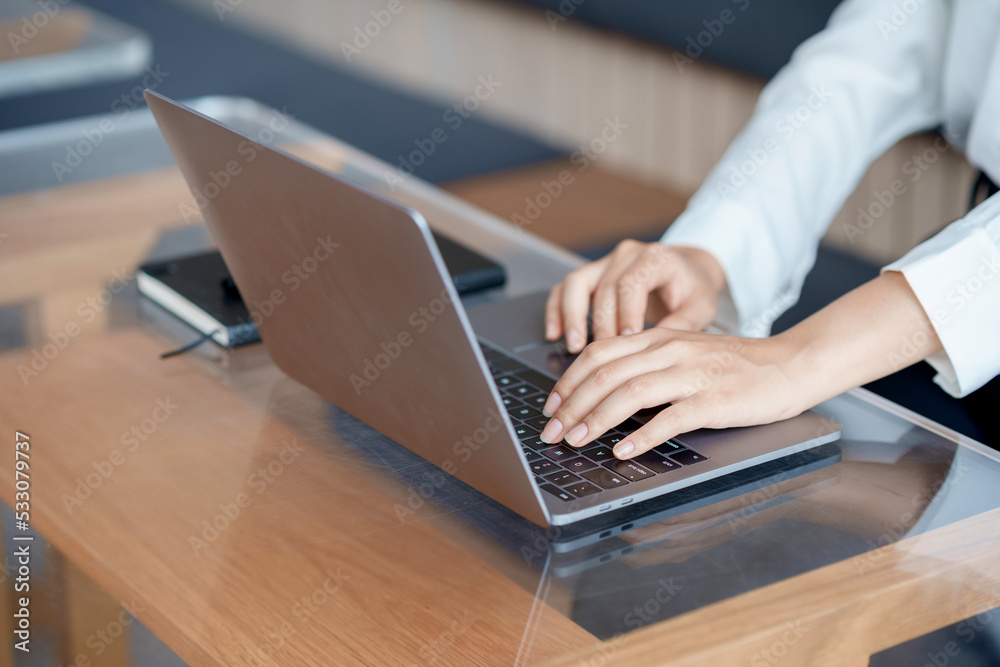 Close-up of hand of businesswoman working together using laptop computer to record and print information for a marketing plan analyze the balance sheet report quarterly financial statement. Close-up of hand of businesswoman working together using laptop computer to record and print information for a marketing plan analyze the balance sheet report quarterly financial statement.