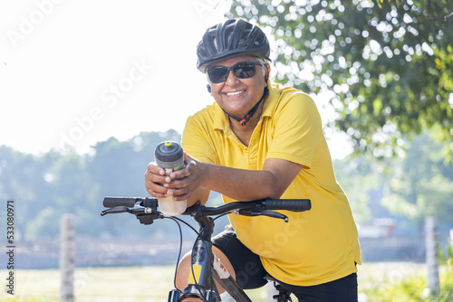 Happy old man leaning on bicycle handlebar 