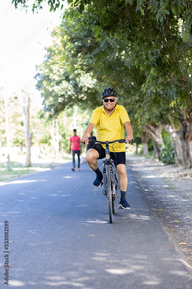 Old man in sportswear riding bicycle outdoors
