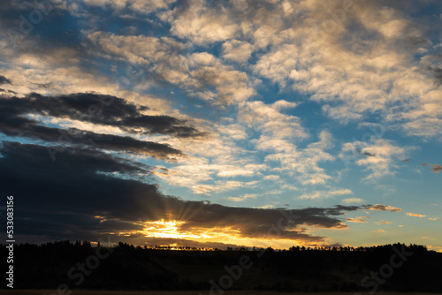 Dawning of new day with brilliant dramatic sunset or sunrise with sun rays through clouds hill and forest trees silhouette representing Heaven or Christian Rapture new beginning as a background