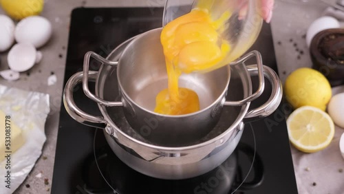 Cooking hollandaise sauce - Woman pours egg yolks into metal steamer pot