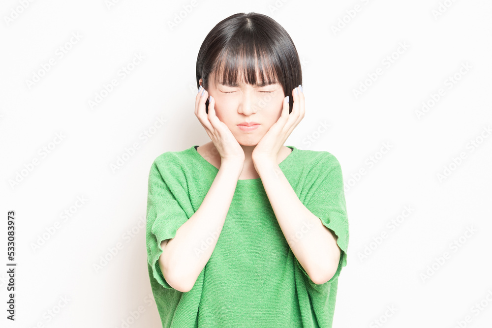 歯が痛くて頬に手を当てる若い女性 歯が痛くて頬に手を当てる若い女性