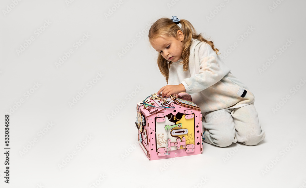 A little girl plays with an educational toy in the form of a house. Banner on the theme of childhood and development. Horizontal orientation, copy space A little girl plays with an educational toy in the form of a house. Banner on the theme of childhood and development. Horizontal orientation, copy space