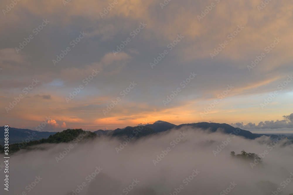 aerial view multicolored sky above the sea of mist..A sea of mist envelops the mountain peaks against the brightly colored sky at sunset..A sea of mist covers the mountain peaks 