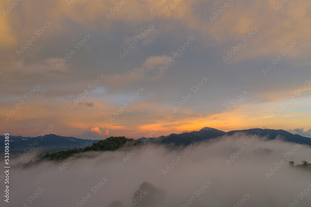 aerial view multicolored sky above the sea of mist..A sea of mist envelops the mountain peaks against the brightly colored sky at sunset..A sea of mist covers the mountain peaks under the colorful