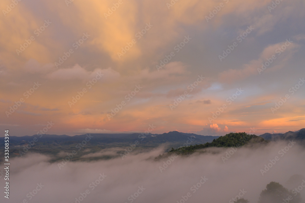 aerial view multicolored sky above the sea of mist..A sea of mist envelops the mountain peaks against the brightly colored sky at sunset..A sea of mist covers the mountain peaks