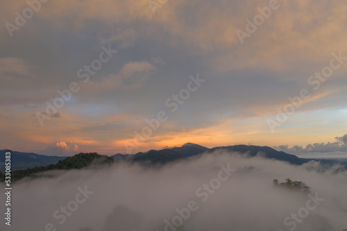 aerial view multicolored sky above the sea of mist..A sea of mist envelops the mountain peaks against the brightly colored sky at sunset..A sea of mist covers the mountain peaks 