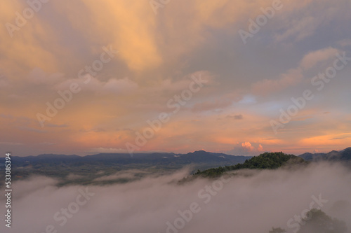 aerial view multicolored sky above the sea of mist..A sea of mist envelops the mountain peaks against the brightly colored sky at sunset..A sea of mist covers the mountain peaks