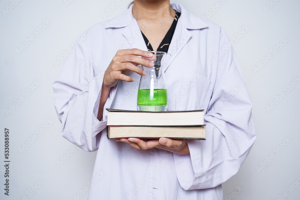 Close-up of scientist hands in a white lab coat holding a stack of books and chemical glassware. Close-up of scientist hands in a white lab coat holding a stack of books and chemical glassware.