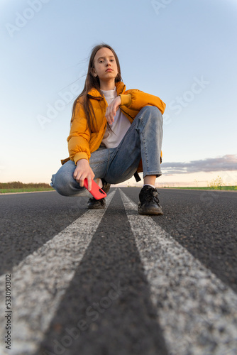 Cool modern teen girl poses on a lonely road
