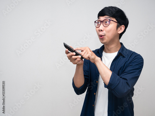 Young asian man gesture press remote tv and feels excited isolated