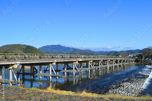 春に歩く京都市嵐山中之島から望む渡月橋と愛宕山