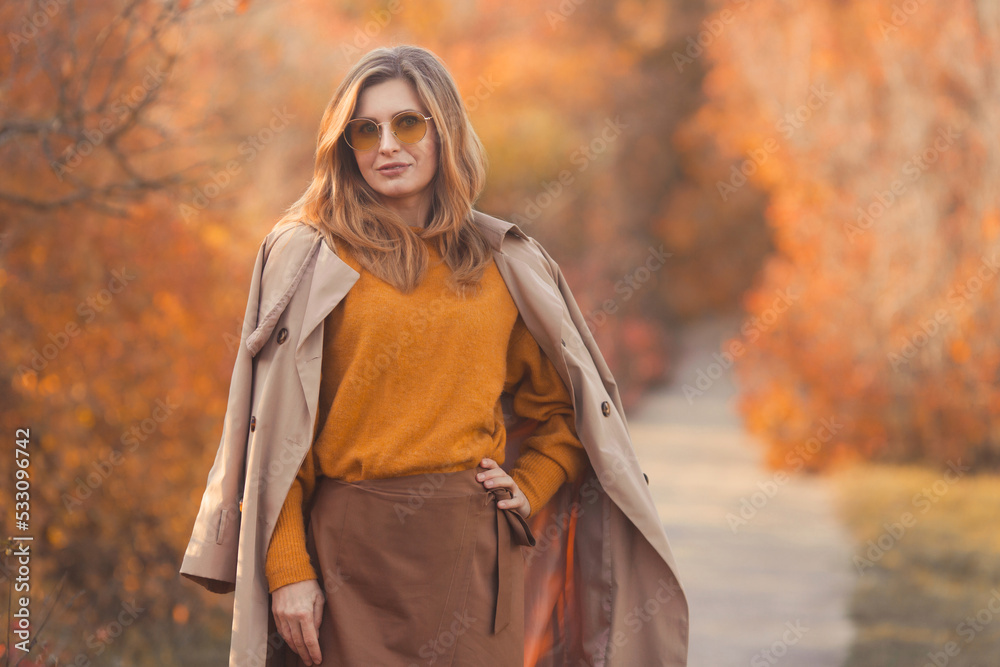 Beautiful woman in trendy and stylish fall outfit in orange and yellow colors on fall forest background Beautiful woman in trendy and stylish fall outfit in orange and yellow colors on fall forest background