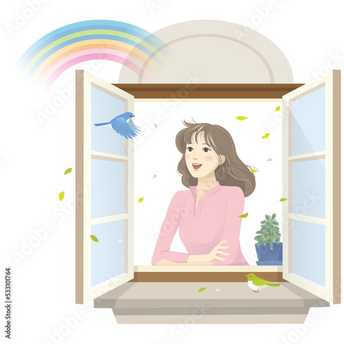 窓から虹を眺める笑顔の女性