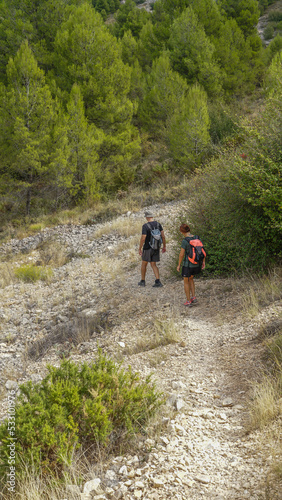 Senderistas irreconocibles de ruta por una senda de piedras en una ladera de montaña