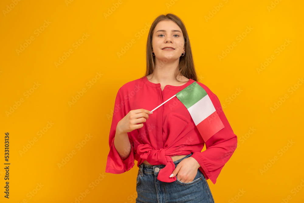 Young woman holds the flag of Italy. Student Exchange Program. Travels to Italy. Studio photo. Copy space. Young woman holds the flag of Italy. Student Exchange Program. Travels to Italy. Studio photo. Copy space.