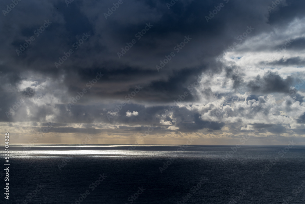 sun breaking through dark clouds over the Atlantic Ocean seen from the Irish coast in spring at the cliffs of moher