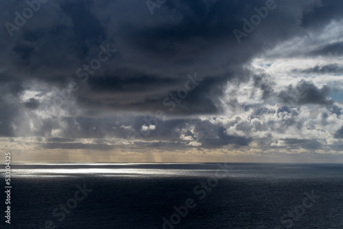 sun breaking through dark clouds over the Atlantic Ocean seen from the Irish coast in spring at the cliffs of moher