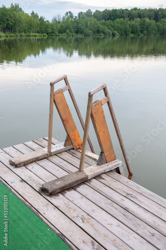 Wooden staircase with railings for descending into the water of a forest pond or lake. Rest in an eco hotel