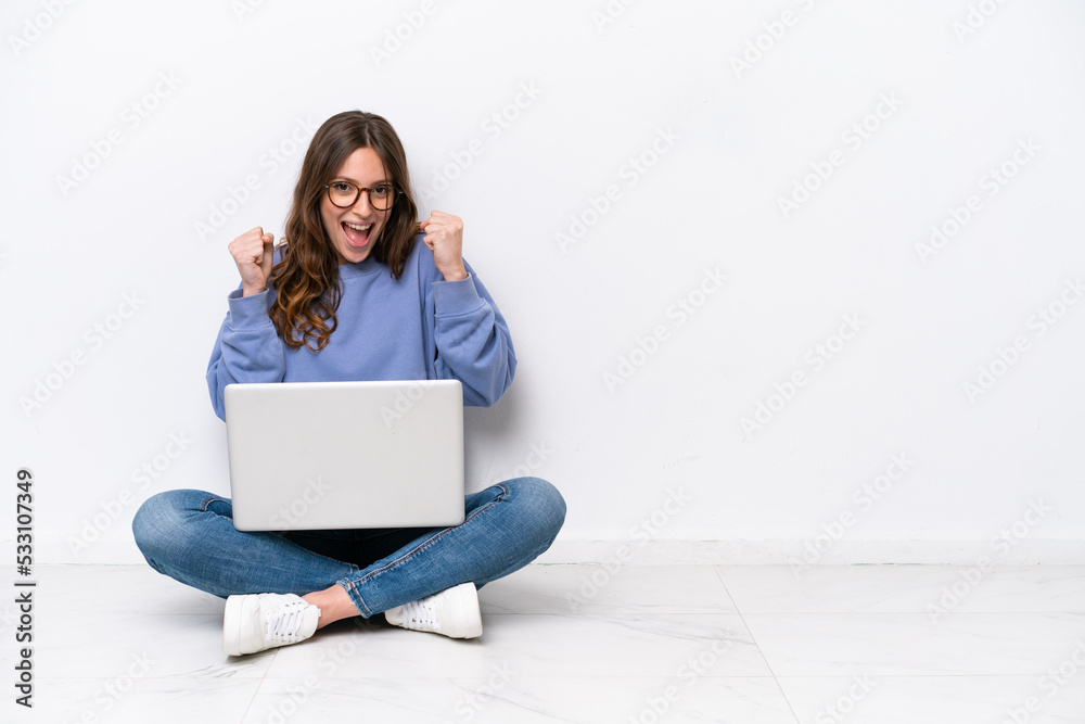 Young caucasian woman with a laptop sitting on the floor isolated on white background celebrating a victory in winner position Young caucasian woman with a laptop sitting on the floor isolated on white background celebrating a victory in winner position