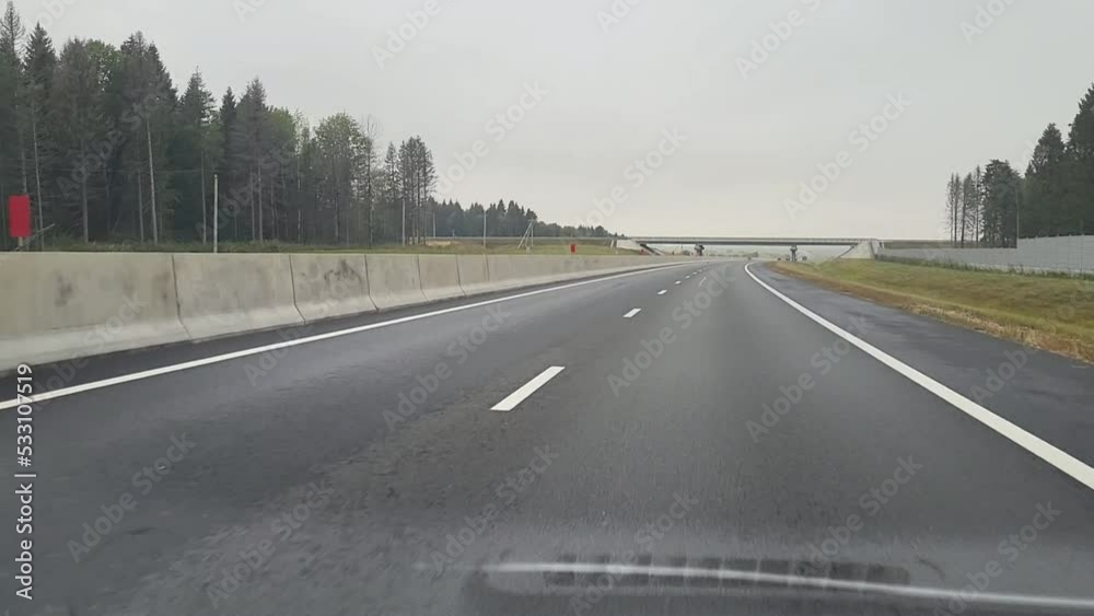 View through the windshield of a moving car. The car is driving along the road on a summer day. Marking of highways, roadsides and road lines. View through the windshield of a moving car. The car is driving along the road on a summer day. Marking of highways, roadsides and road lines.