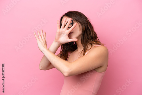 Young caucasian woman isolated on pink background nervous stretching hands to the front