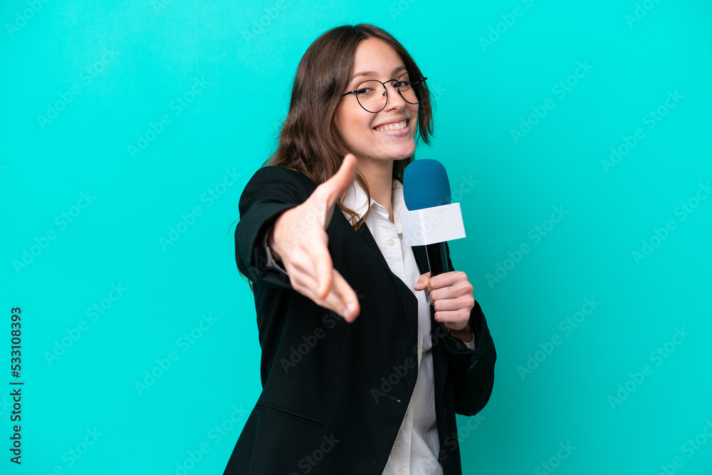 Young TV presenter woman isolated on blue background shaking hands for closing a good deal Young TV presenter woman isolated on blue background shaking hands for closing a good deal