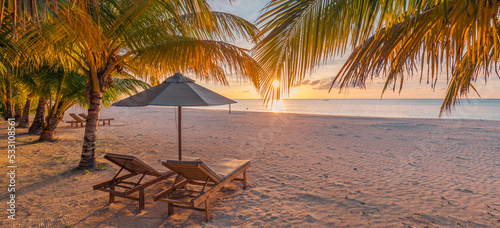 Beautiful panoramic tropical beach. Sunset summer island landscape with couple chairs umbrella palm leaves calm sea shore, coast. Romantic travel panorama honeymoon destination banner vacation holiday