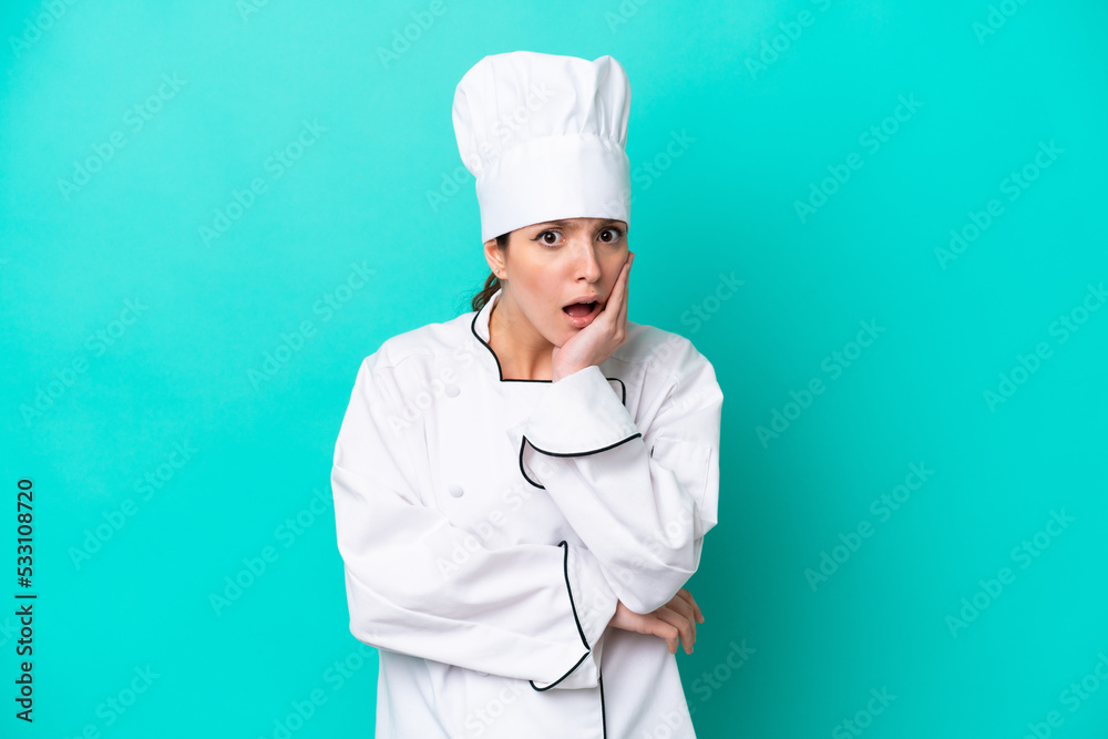 Young caucasian chef woman isolated on blue background surprised and shocked while looking right Young caucasian chef woman isolated on blue background surprised and shocked while looking right