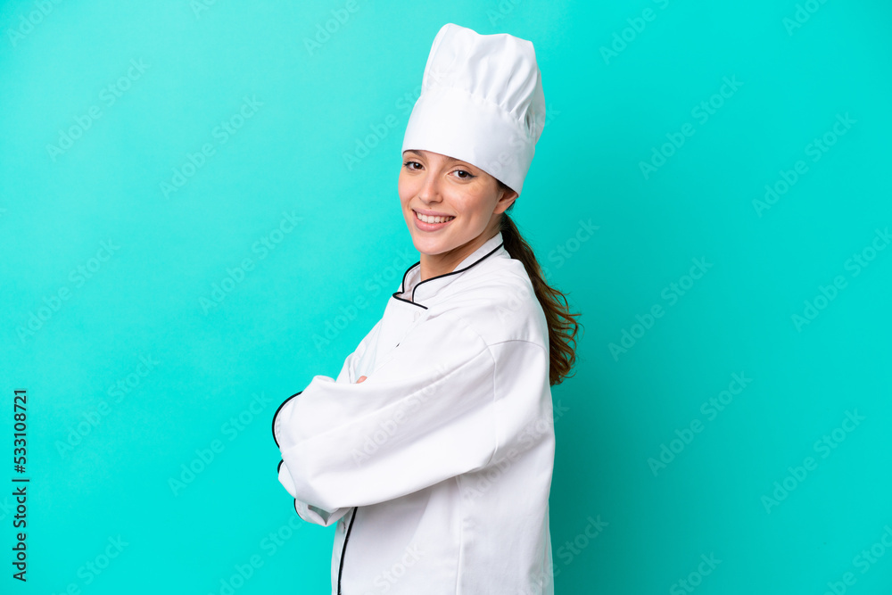 Young caucasian chef woman isolated on blue background with arms crossed and looking forward Young caucasian chef woman isolated on blue background with arms crossed and looking forward