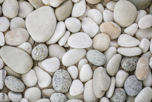 White pebbles background, simplicity, daylight, rounded stones. Natural bright pebbles stones, relaxing peaceful zen decoration. Artistic backdrop wallpaper in nature. Macro pattern